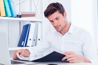 A business man reading a printed out report at his desk