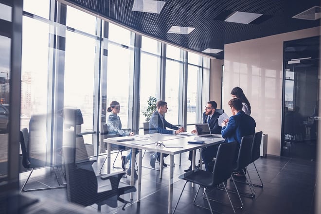 A team of employees discussing work in a glass walled conference room