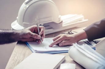 Close up of a construction worker signing insurance paperwork