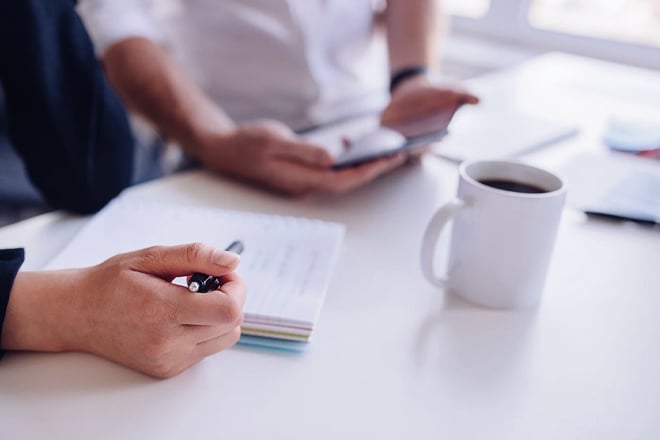 Close up of two coworkers sitting together analyzing documents
