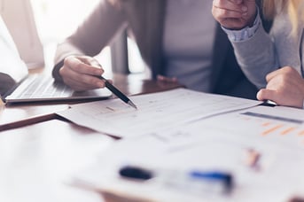 Close up of two employees reviewing documents line by line with a pen