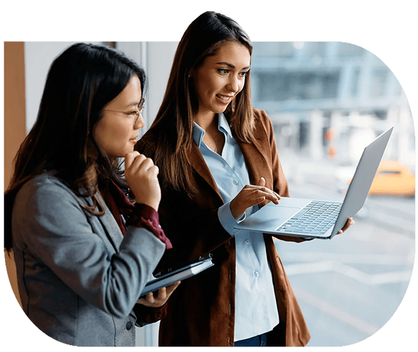 Two brokers standing together reviewing information on a laptop