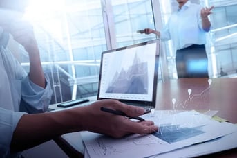 Professional analyzing data on laptop with digital chart overlay visualization