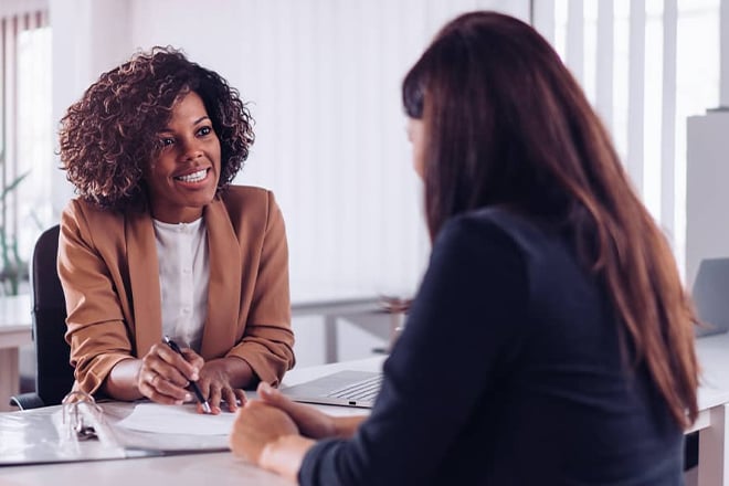 Two businesswomen in meeting discussing documents at desk