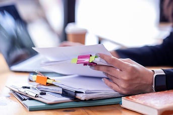 Professional reviewing documents with colorful tabs at desk with coffee
