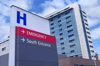 Modern hospital building with directional signs pointing to Emergency and South Entrance