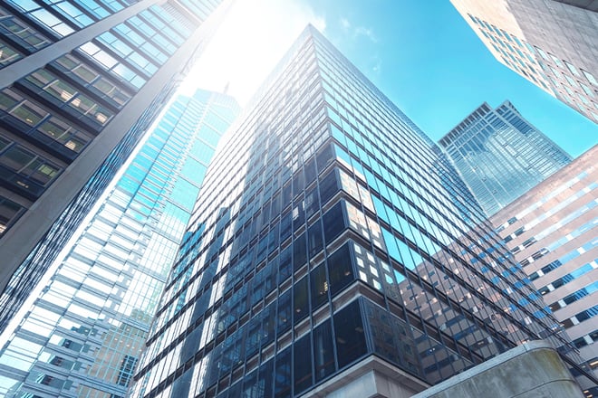 A view looking up at large real estate buildings in a city center.