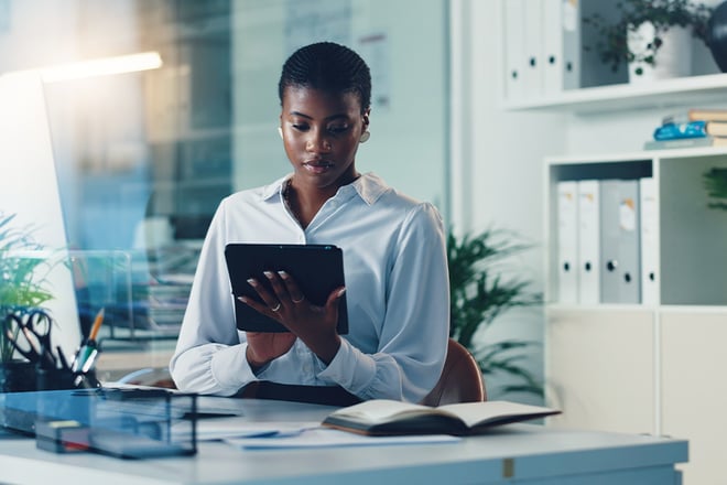 A property manager reading on a tablet while sitting at their desk inside an office building.
