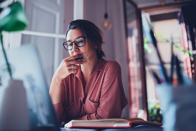 Young businesswoman thinking about something while sitting in front of a laptop
