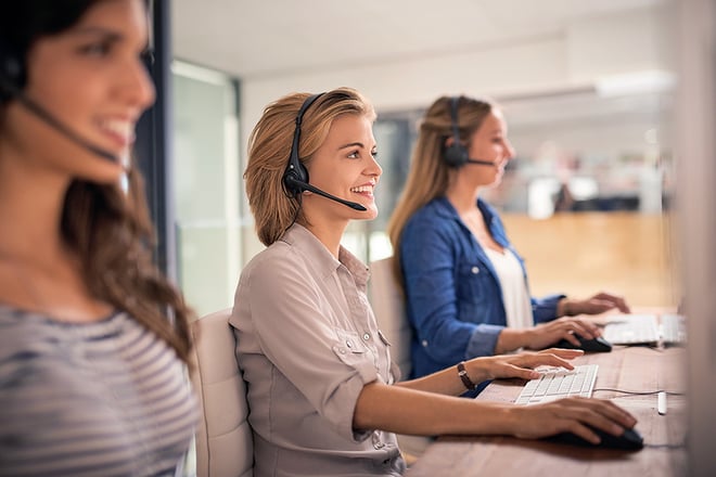 A customer support team wearing headsets working in an offices setting.