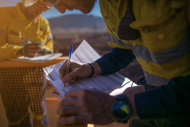 Closeup of a construction worker signing insurance paperwork.
