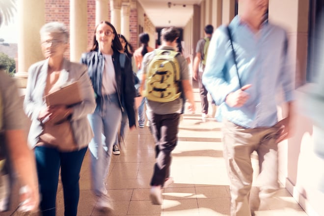 An outdoor walkway on a school campus filled with students and teachers.