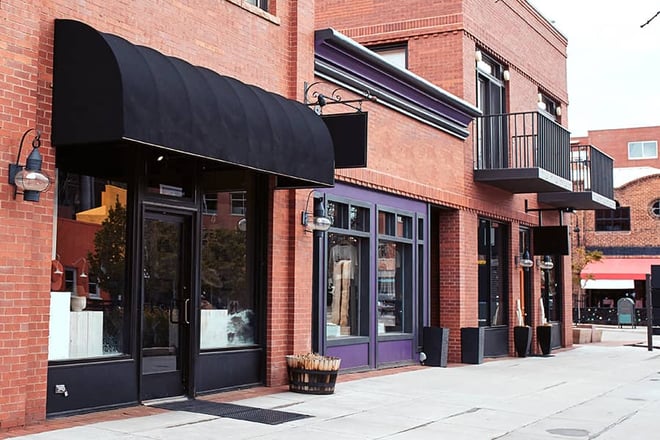 A row of brick buildings that house offices, shops, and retail businesses.