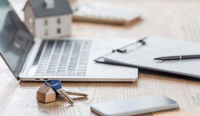 Close up of laptop and keys on a desk.