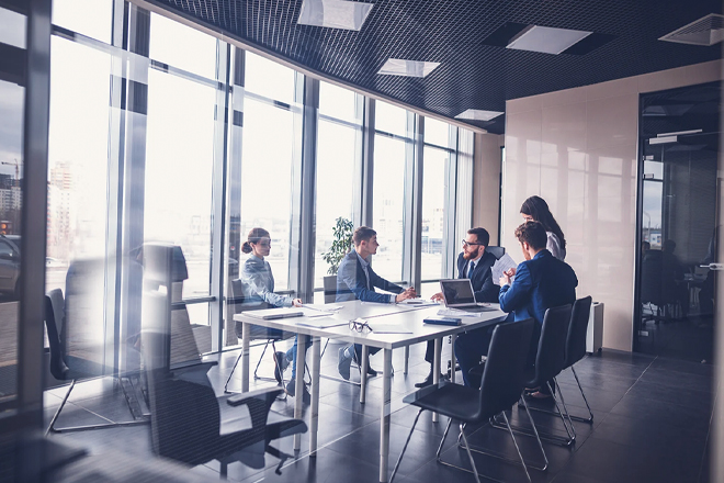 A team of employees discussing work in a glass walled conference room