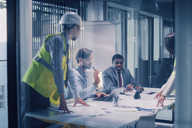 Executives and Engineers meet in a conference room to review construction plans, align budget and schedule