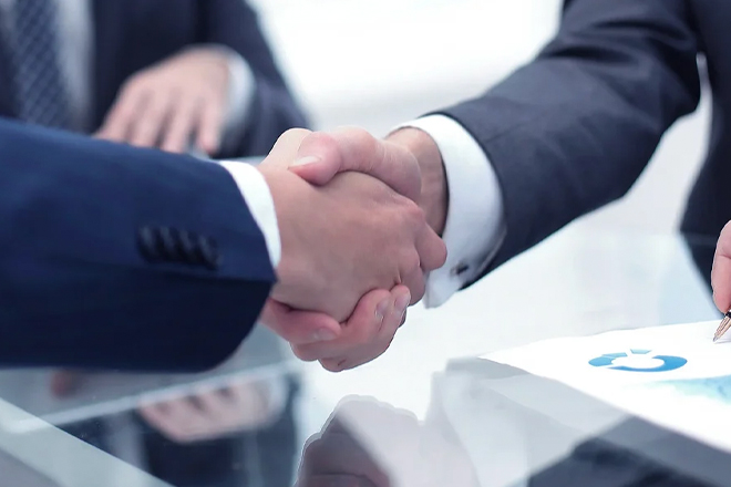 Close-up of business handshake over desk with documents