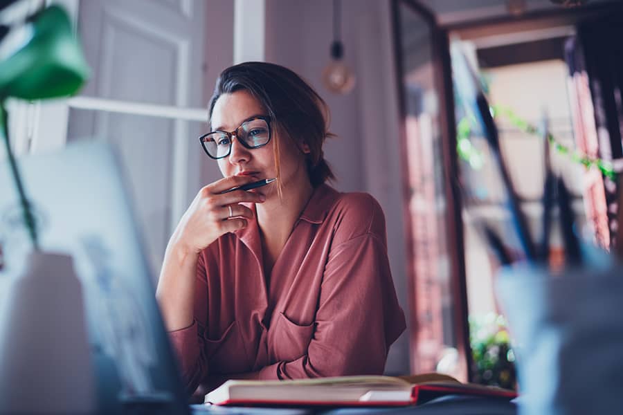 Young businesswoman thinking about something while sitting in front of a laptop