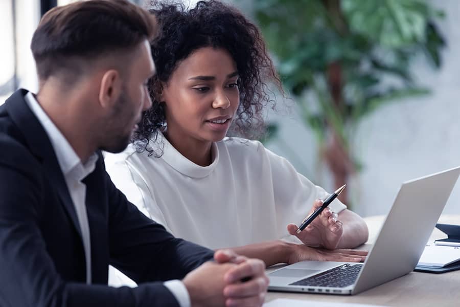 Two people reviewing information on a laptop together.