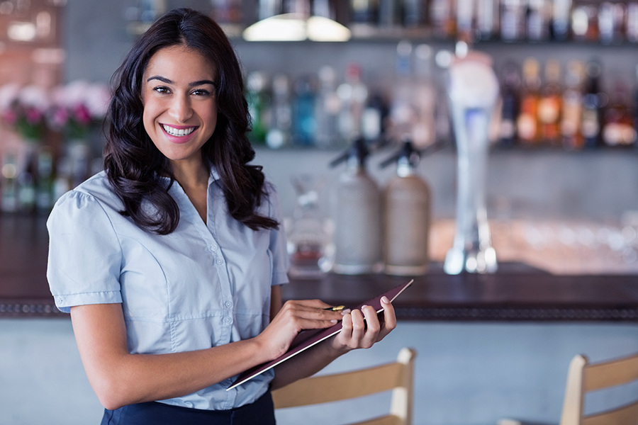 A smiling waitress holding pen and file.