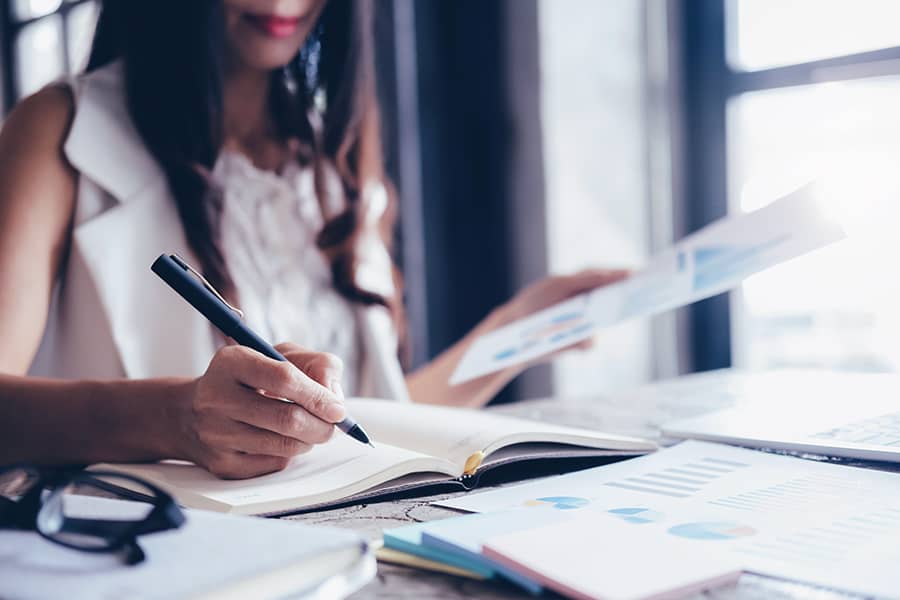 A close up of a woman reviewing documents at a desk.