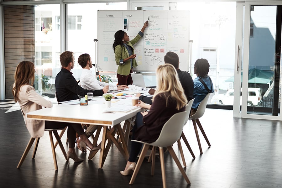 A team of people reviewing information on whiteboard in a conference room.