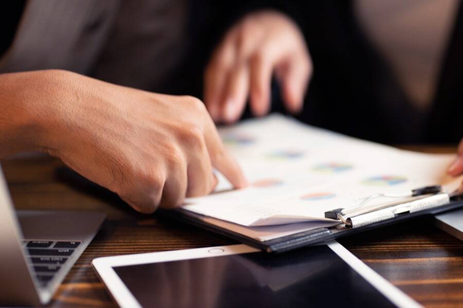 Close up of two people reviewing printed and digital documents.