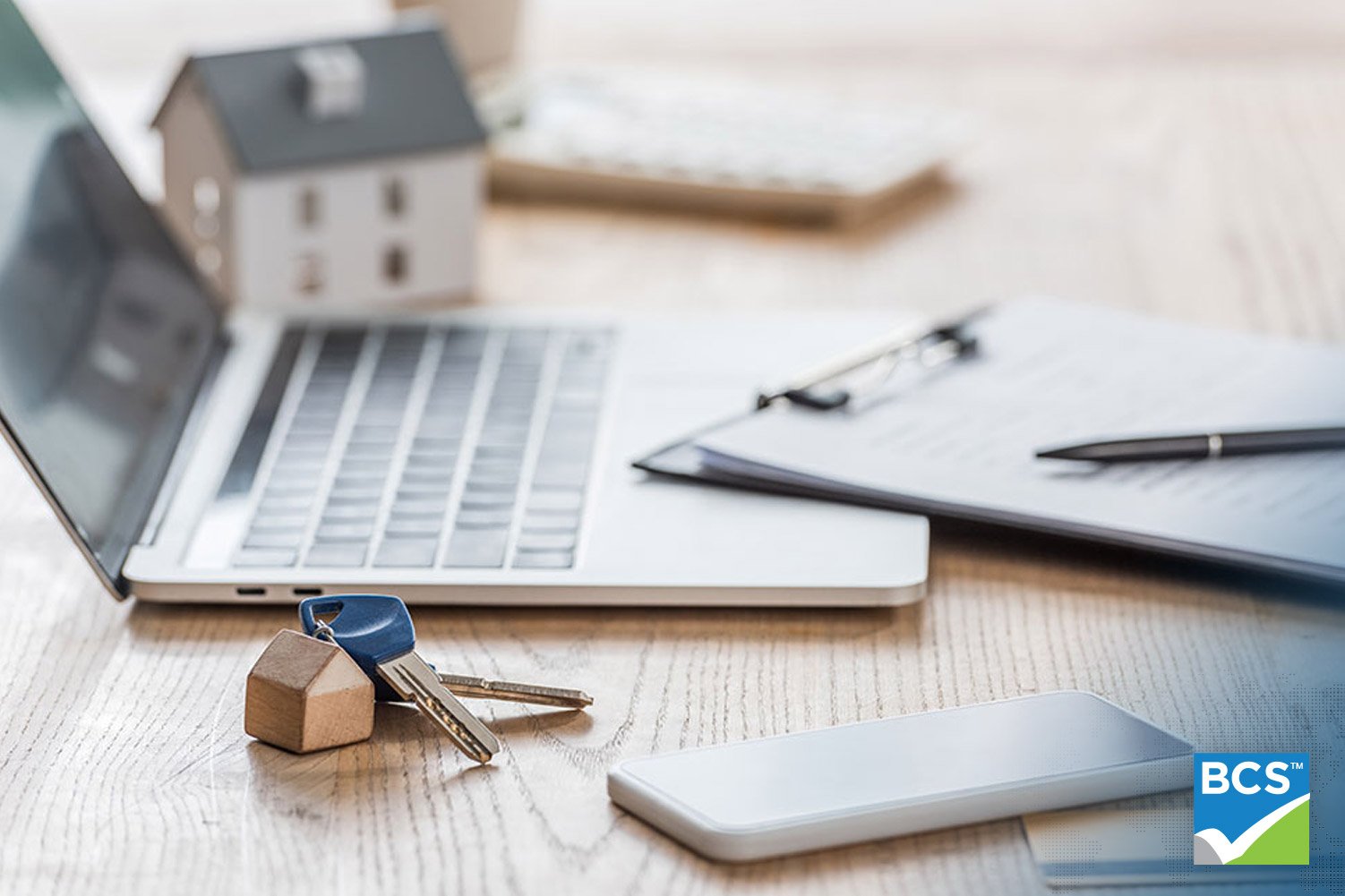 close up of laptop and notepad and house keys sitting on table