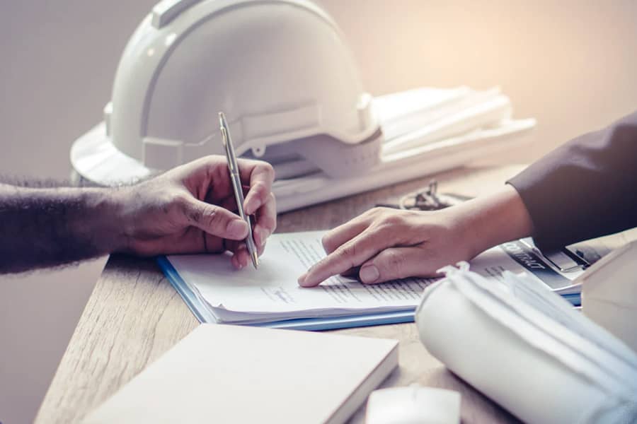 construction worker signing insurance papers on desk